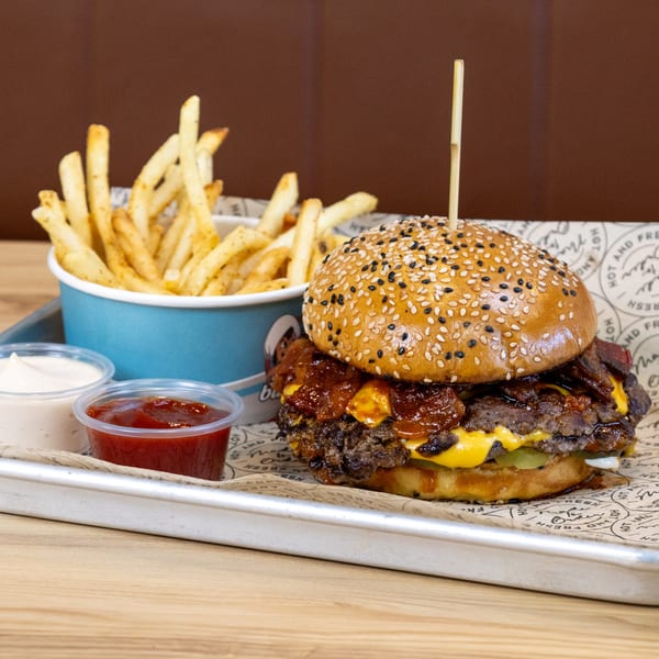 Sindbad Burger's double cheeseburger with bacon jam, fries, ketchup, and mayonnaise on a tray.