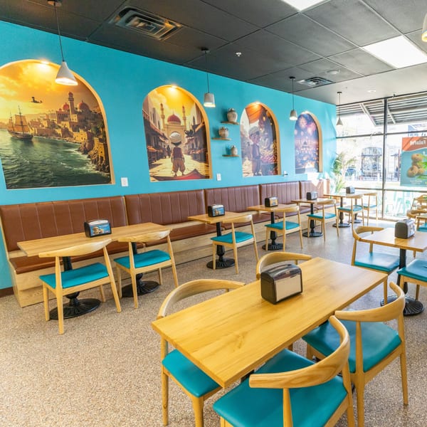 Interior of Sindbad Burger with teal walls, brown booths, light wood tables, and teal chairs.