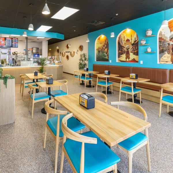 Interior of Sindbad Burger with light wood tables, blue chairs, and vibrant blue walls with arched murals.