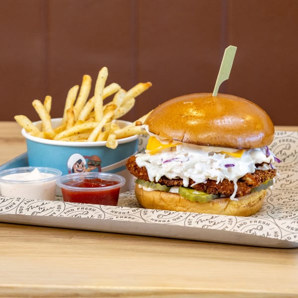 Sindbad Burger's crispy chicken sandwich with coleslaw, pickles, cheese, fries, ketchup, and mayo.