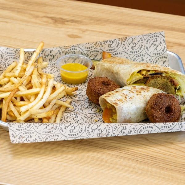 Sindbad Burger's falafel wraps, golden fries, and dipping sauce on a branded paper-lined tray.